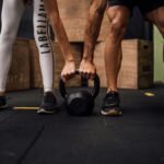 Hombre y mujer sujetando una kettlebell en el gimnasio, realizando ejercicio en conjunto