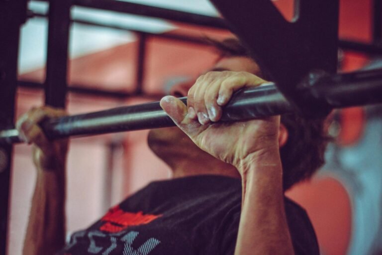 Hombre realizando ejercicio de pull-up en el gimnasio, enfocado en el esfuerzo físico y la fuerza