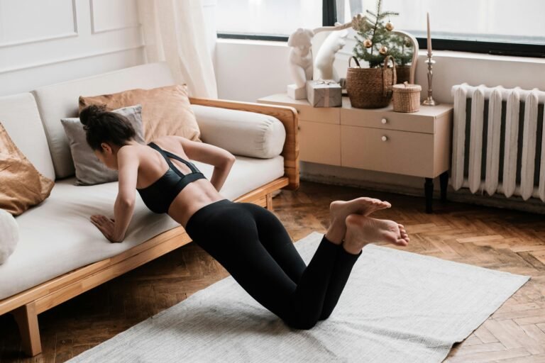 Mujer haciendo flexiones modificadas apoyada en un sofá en la comodidad de su hogar