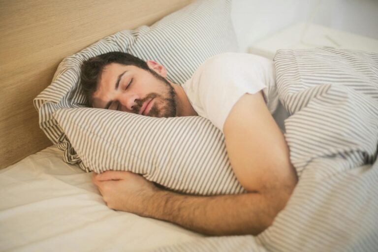 Hombre durmiendo plácidamente sobre una almohada con ropa de cama a rayas.