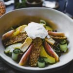 Plato de ensalada con tempeh, vegetales frescos y una porción de aderezo cremoso.