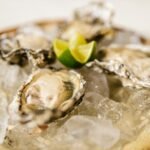 Ostras frescas servidas sobre hielo con rodajas de lima, un plato elegante y fresco.