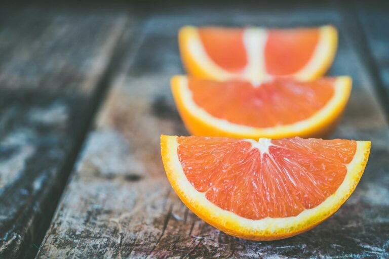 Rodajas frescas de naranja colocadas sobre una mesa de madera rústica.