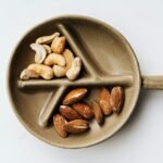 Surtido de anacardos y almendras presentados en un plato de cerámica decorativo sobre un fondo blanco limpio.