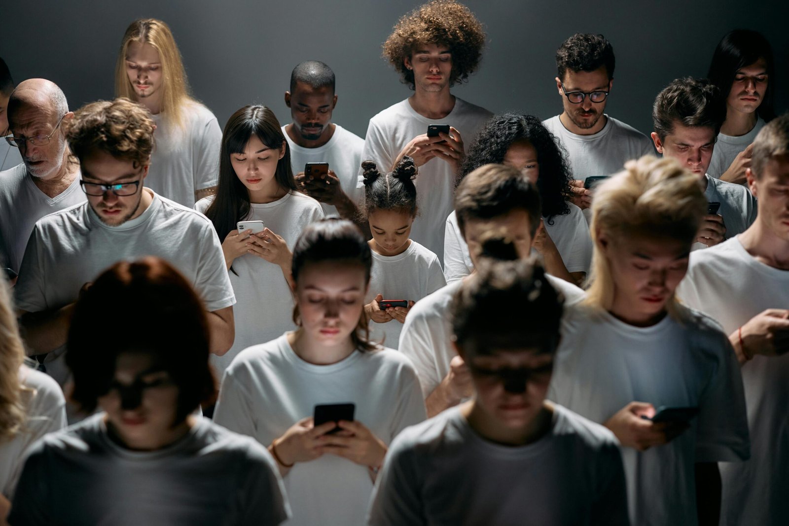 Una multitud diversa de personas que utilizan teléfonos inteligentes, lo que resalta las conexiones sociales modernas y el aislamiento.